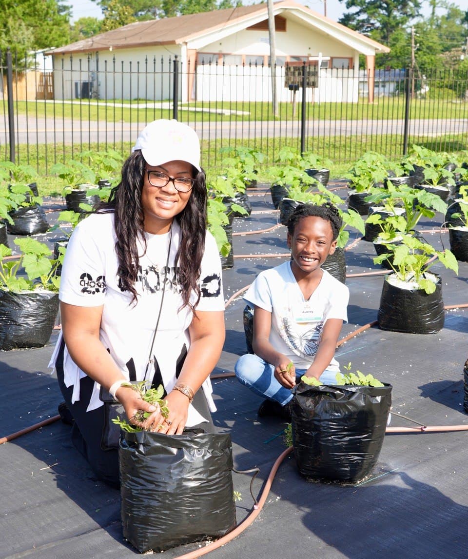A Living in Purpose staff member and a student planting together in the community garden