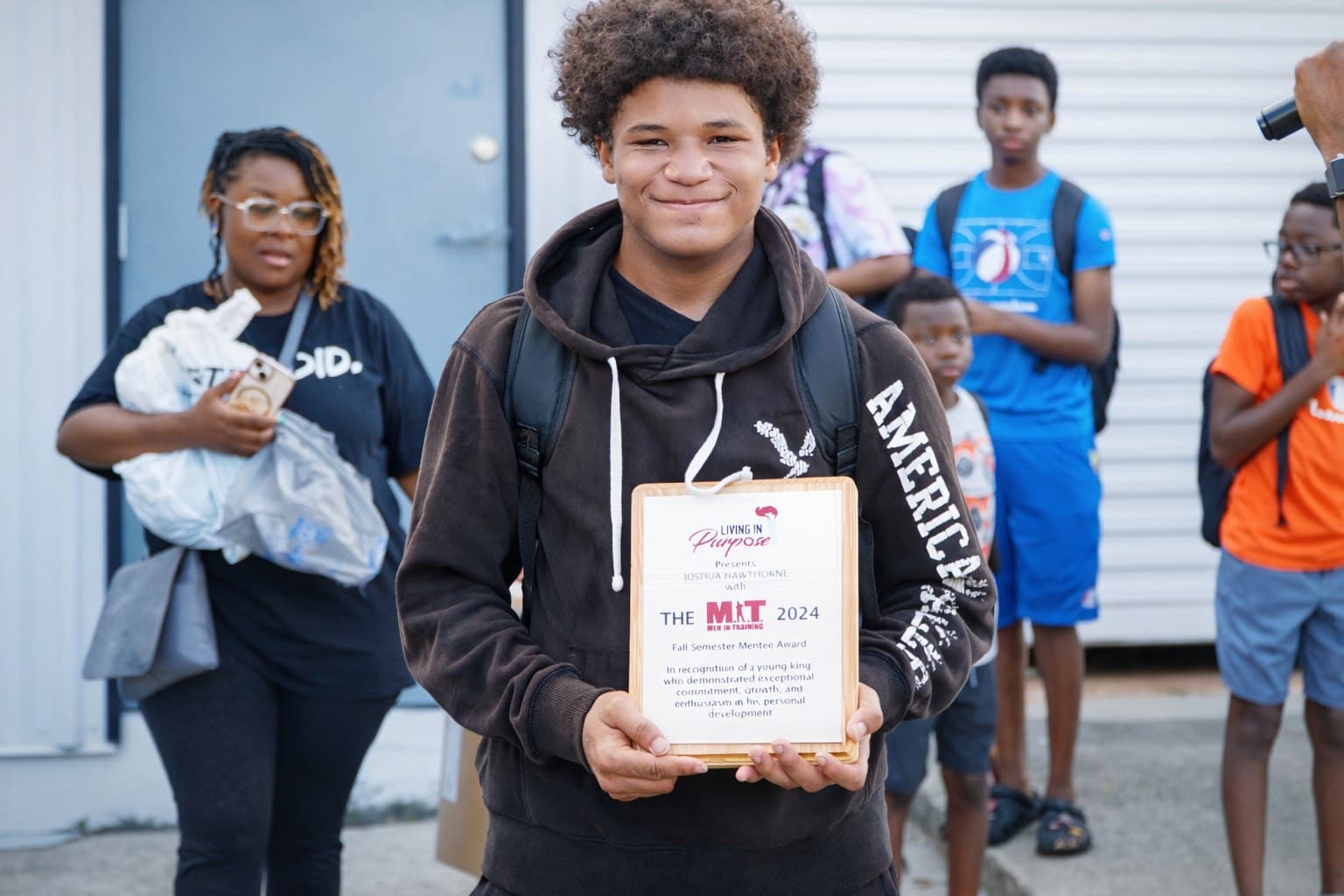 A Living in Purpose teen holding his Men in Training recognition award