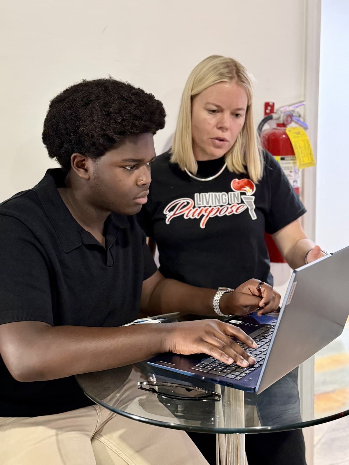 A Living in Purpose mentor working through a laptop project with a student